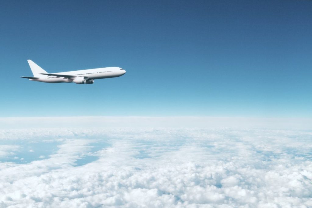 white airplane flying above white clouds in blue sky. 3d rendering